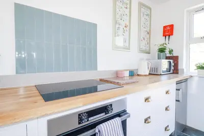 a kitchen with white cabinets and a wooden counter top at Hilldene in Tintagel