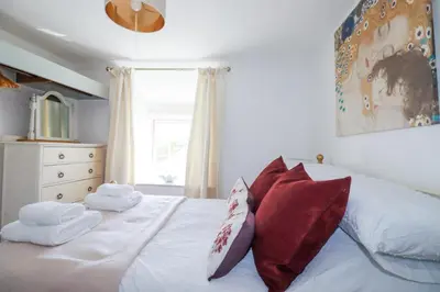 a bedroom with a white bed with red pillows at Hilldene in Tintagel