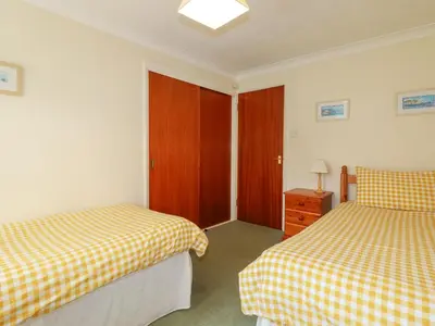 a bedroom with two beds and a wooden door at Godrevy View in St Ives