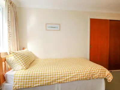 a bedroom with a bed with a checkered blanket on it at Godrevy View in St Ives