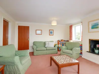 a living room with two chairs and a fireplace at Godrevy View in St Ives