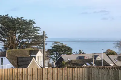 a fence with houses and the ocean in the background at Azur in St Ives