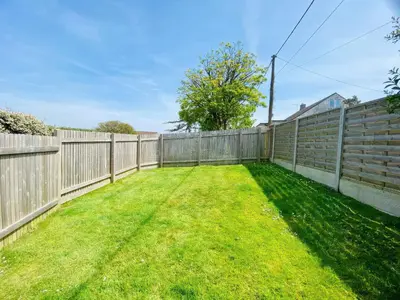 a backyard with a fence and green grass at Hawthorn in Bude