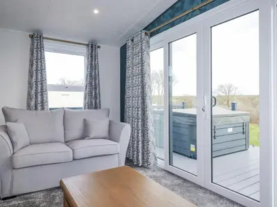 a living room with a couch and a sliding glass door at The Maples, No 48 in St Austell