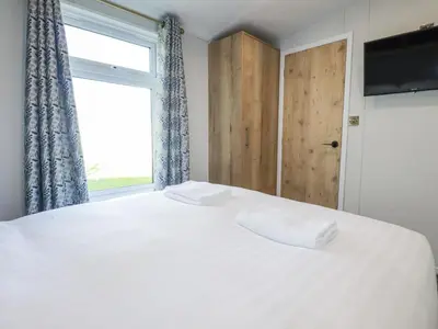 a bedroom with a large white bed with a window at The Maples, No 48 in St Austell