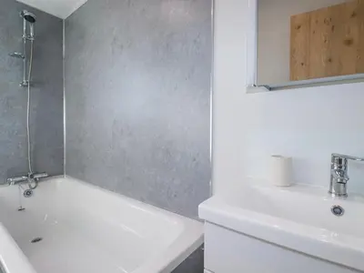 a white bathroom with a sink and a bath tub at The Maples, No 48 in St Austell