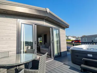 a deck with a glass table and a hot tub at The Maples, No 48 in St Austell