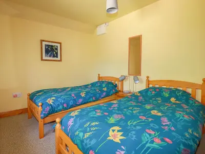 a bedroom with two beds with blue sheets at The Old Piggery in Truro