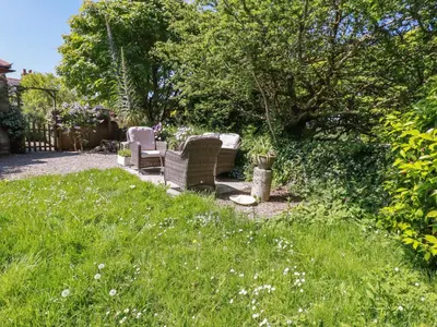 a garden with two chairs and a table at The Old Piggery in Truro
