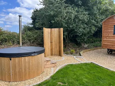 a backyard with a hot tub and a wooden fence at Kilden Hut - Perranwell Station in Perranwell