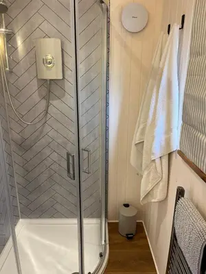 a shower with a glass door in a bathroom at Kilden Hut - Perranwell Station in Perranwell
