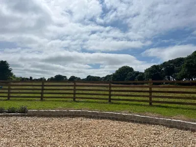 a wooden fence in front of a field at Kilden Hut - Perranwell Station in Perranwell