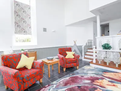 a living room with two chairs and a table at Trelowth Chapel in St Austell