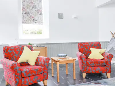 two chairs and a table in a living room at Trelowth Chapel in St Austell