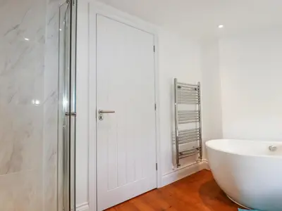 a bathroom with a white door and a tub and a sink at Trelowth Chapel in St Austell