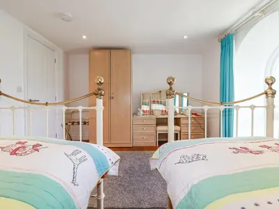 two beds in a bedroom with blue curtains at Trelowth Chapel in St Austell
