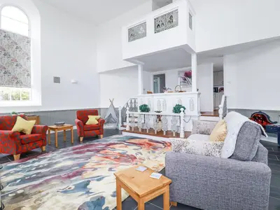 a living room with a couch and chairs and a rug at Trelowth Chapel in St Austell