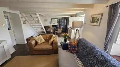 a living room with a couch and chairs and stairs at Sophie's Cottage in Philleigh
