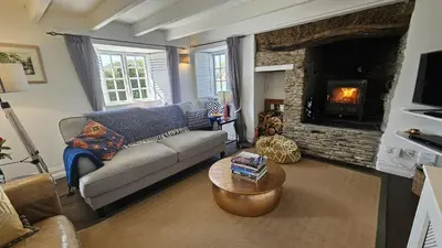 a living room with a couch and a fireplace at Sophie's Cottage in Philleigh