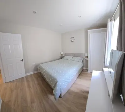 a white bedroom with a bed and a wooden floor at Acklington 2 bedroom property in Menheniot
