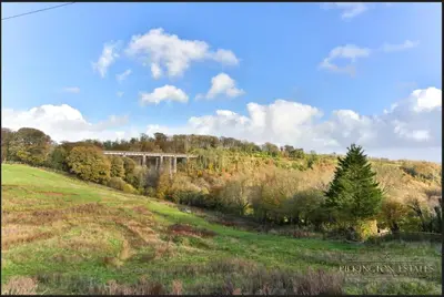 a bridge in the middle of a field with trees at Acklington 2 bedroom property in Menheniot