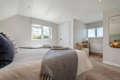 a white bedroom with a large bed and two windows at 4 Bed in St. Merryn oc-f31095 in St Merryn