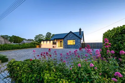 a house with a garden with flowers in the foreground at 4 Bed in St. Merryn oc-f31095 in St Merryn