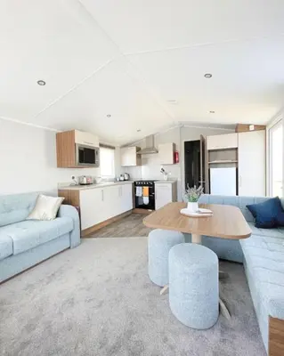 a living room with a blue couch and a table at Ocean Breeze-Haven Perran Sands Holiday Park in Perranporth