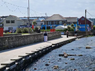 a group of people standing on a pier next to a river at Ocean Breeze-Haven Perran Sands Holiday Park in Perranporth