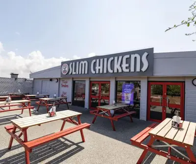 a group of picnic tables in front of a restaurant at Ocean Breeze-Haven Perran Sands Holiday Park in Perranporth