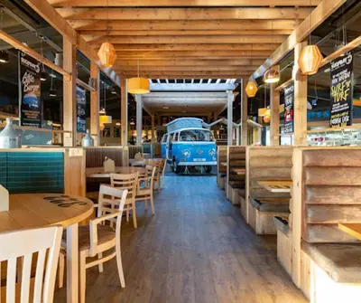 an empty restaurant with an old van in the background at Ocean Breeze-Haven Perran Sands Holiday Park in Perranporth