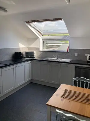 a kitchen with a window and a sink and a table at Bossiney Lodge Apartment in Tintagel