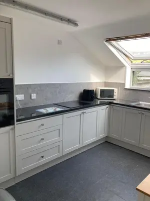 a kitchen with white cabinets and a window at Bossiney Lodge Apartment in Tintagel