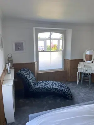a bedroom with a bed and a window at Bossiney Lodge Apartment in Tintagel