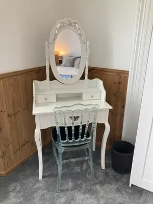 a white dressing table with a mirror and a chair at Bossiney Lodge Apartment in Tintagel