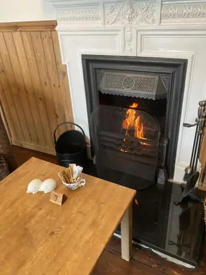 a living room with a fireplace and a wooden table at Bossiney Lodge Apartment in Tintagel