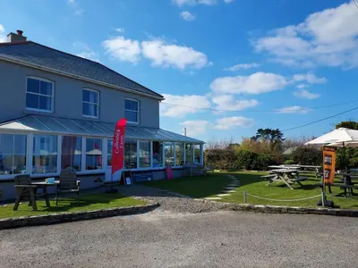 a building with a picnic table in front of it at Bossiney Lodge Apartment in Tintagel