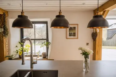 a kitchen with three lights hanging over a sink at 5 Star Large Farmhouse Near The Beach With Hot Tub & Sauna - Porth, Near Newquay in Saint Columb Minor