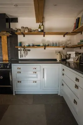 a kitchen with white cabinets and black counter tops at 5 Star Large Farmhouse Near The Beach With Hot Tub & Sauna - Porth, Near Newquay in Saint Columb Minor