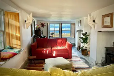 a living room with a red couch and a fireplace at Old Chapel House in Tintagel