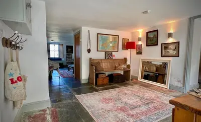 a living room with a fireplace and a piano at Old Chapel House in Tintagel