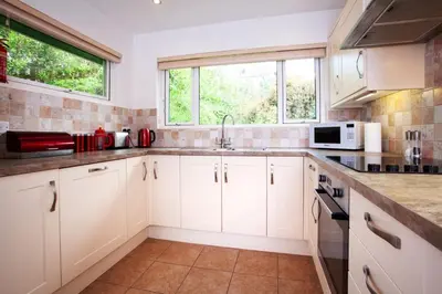 a kitchen with white cabinets and a sink and a window at Creek View in Feock