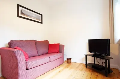 a living room with a pink couch and a tv at Creek View in Feock