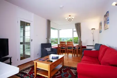 a living room with a red couch and a table at Creek View in Feock
