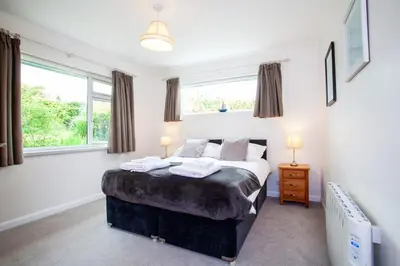 a bedroom with a bed and two windows at Creek View in Feock