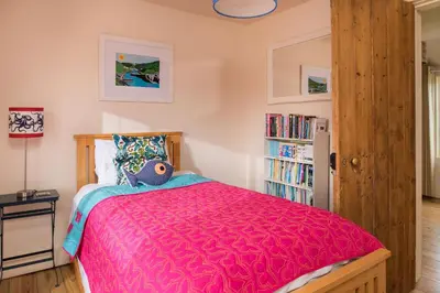 a bedroom with a bed with a red comforter at Trevigue Cottage in Bude