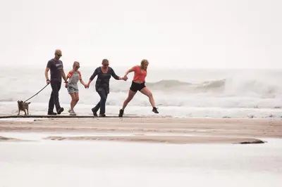 a group of people walking a dog on the beach at Trevigue Cottage in Bude