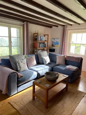 a blue couch in a living room with a table at Trevigue Cottage in Bude