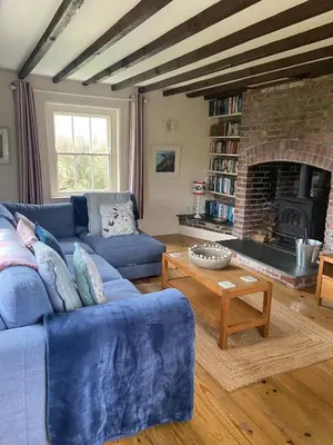 a living room with a blue couch and a fireplace at Trevigue Cottage in Bude