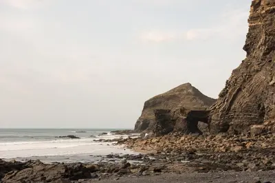 a rocky beach with the ocean and a rocky cliff at Trevigue Cottage in Bude